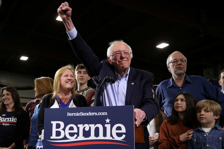 Bernie Sanders with his fist in the air surrounded by supporters