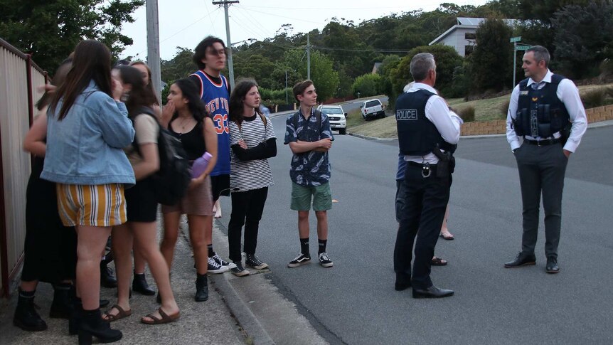 Locals gather near the scene of a siege in Launceston, watched over by Tasmanian Police.
