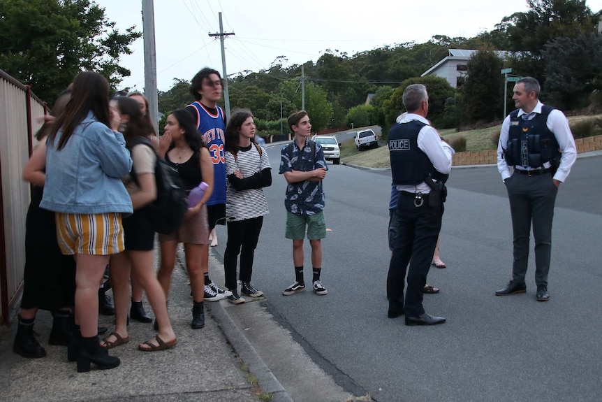 Locals gather near the scene of a siege in Launceston, watched over by Tasmanian Police.
