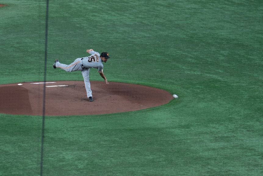 A baseball player standing on one leg as he pitches a ball 