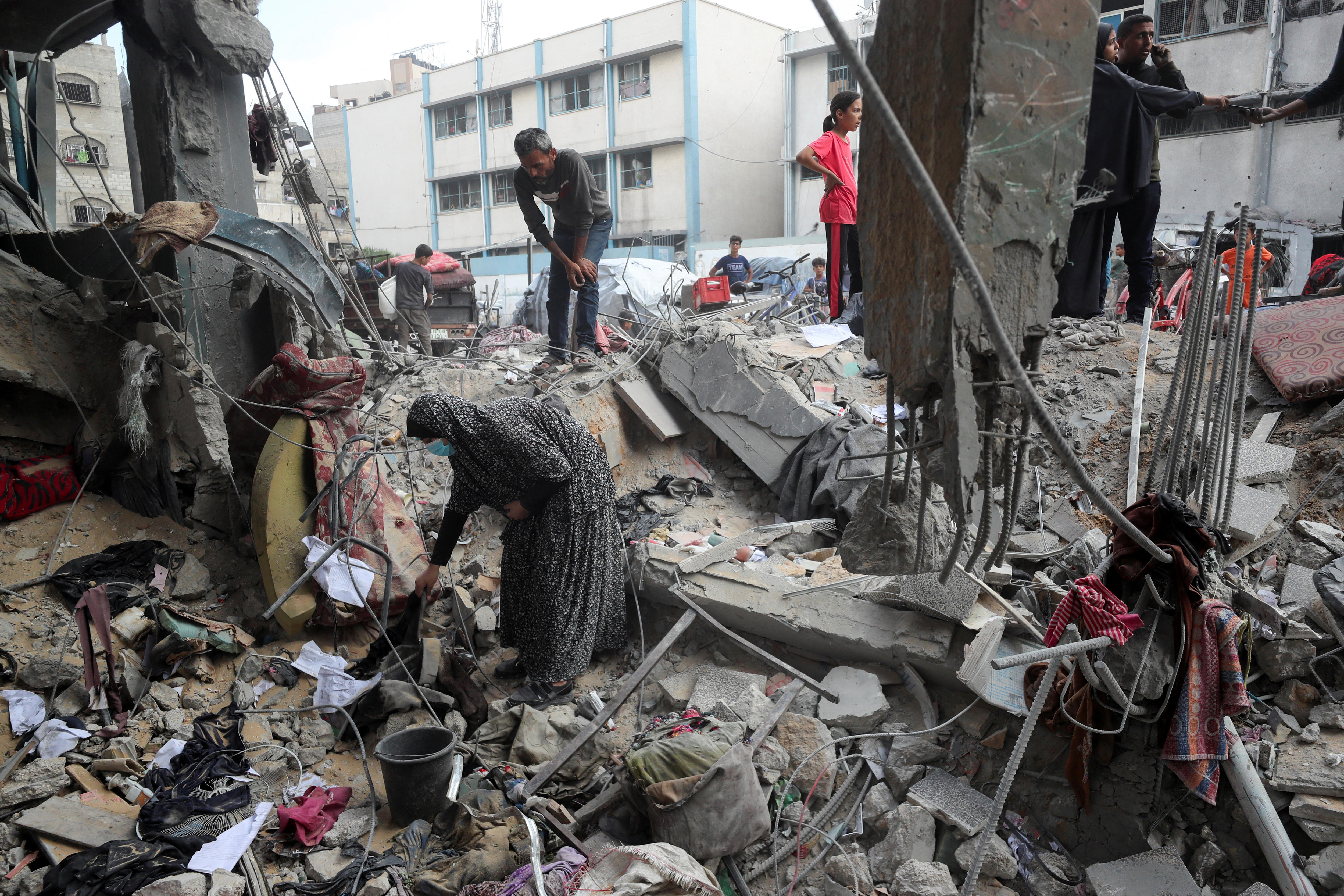 People combing through the rubble of a partially destroyed school building.