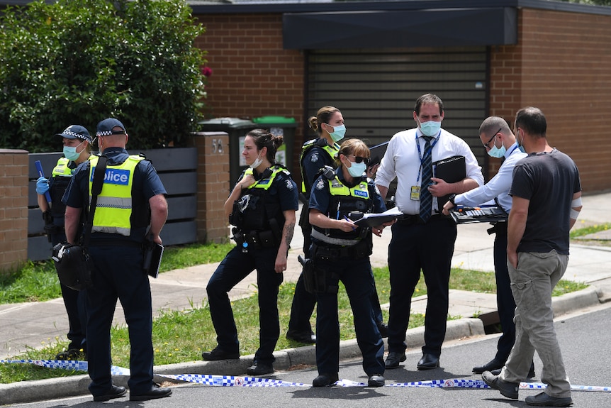 A number of police officers speak with a man on a suburban street in Tullamarine.