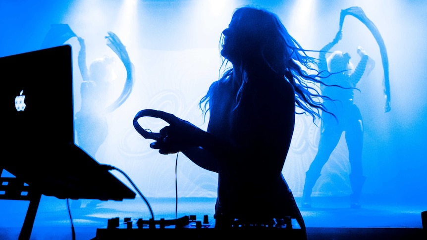 a silhouette of female dj with dancers behind her