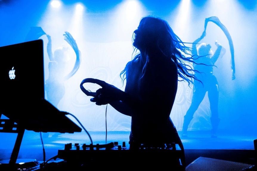 a silhouette of female dj with dancers behind her