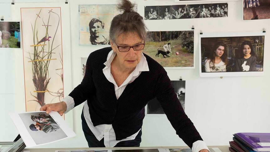 In this self portrait photographer Ruth Maddison is standing over a table looking at prints from her Eden series.