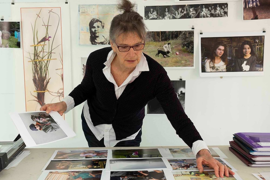 In this self portrait photographer Ruth Maddison is standing over a table looking at prints from her Eden series.