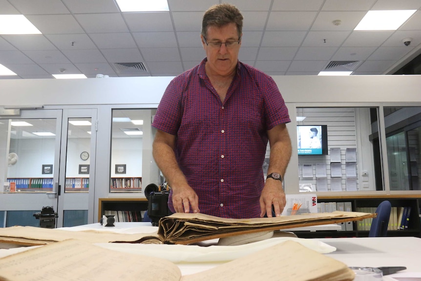 Dr Matthew Stephen flips through archival books.