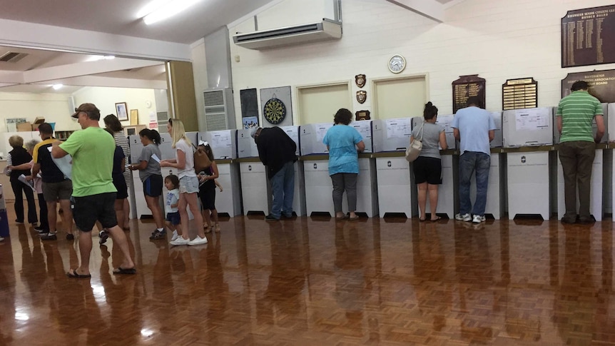 Voters at polling booths in a hall.
