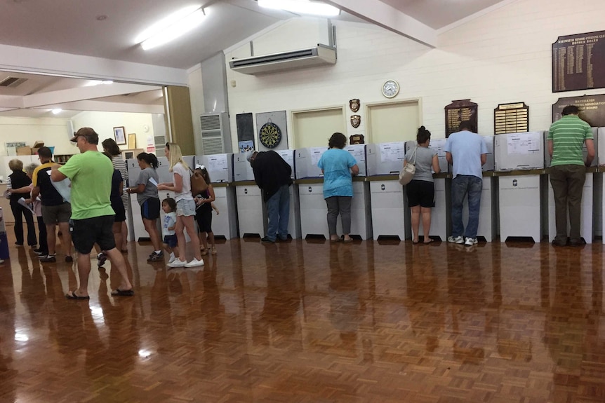 Voters at polling booths in a hall.