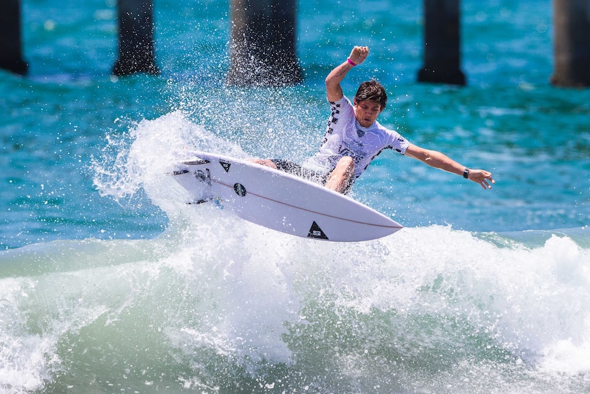 Cooper Chapman surfing on top of a wave at Huntington Beach in California.