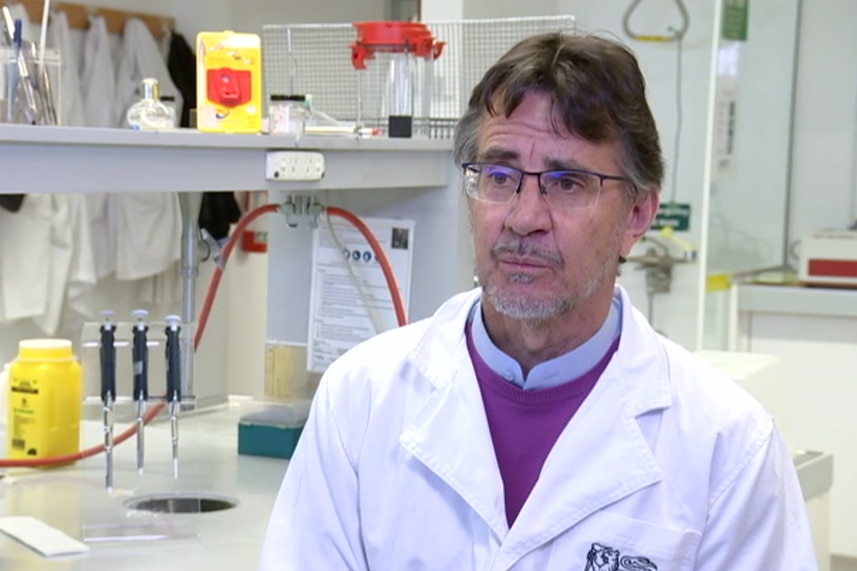 Person in a lab coat in front of scientific apparatus