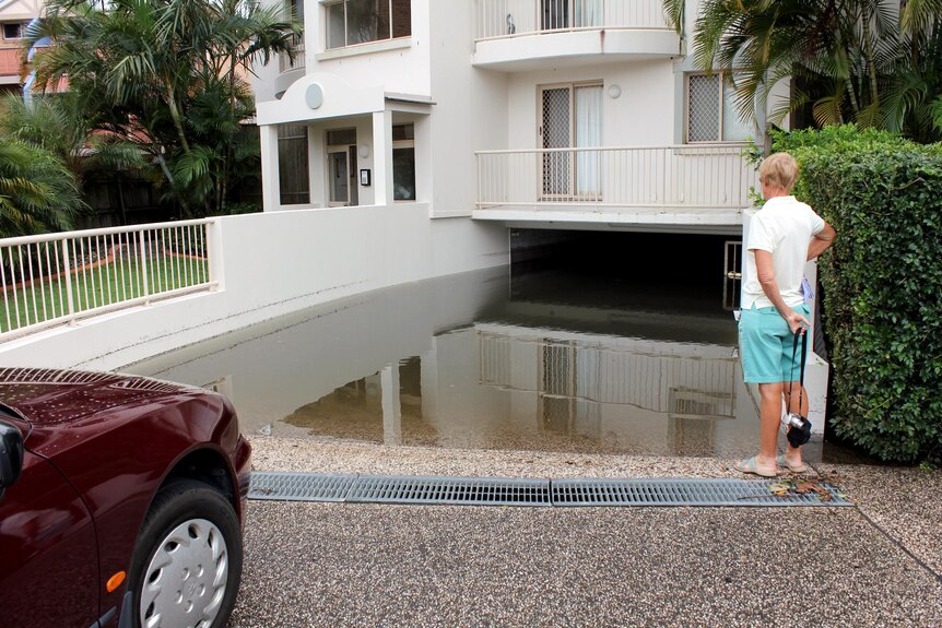 A woman looks into a flooded carpark, where her car is parked, at a unit block in Maroochydore on March 23.