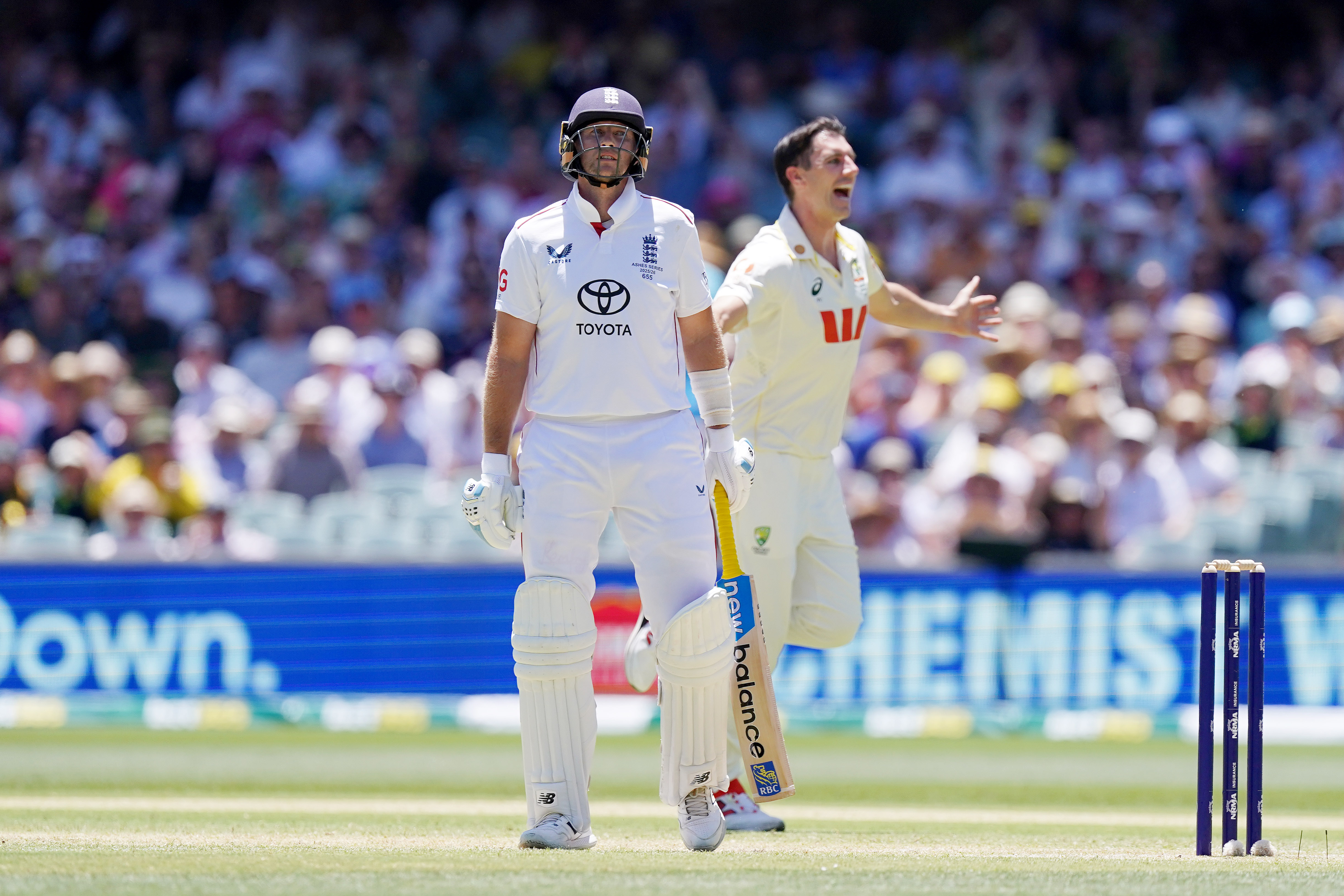 El bateador de Inglaterra Joe Root echa la cabeza hacia atrás mientras Pat Cummins celebra durante una prueba de críquet.