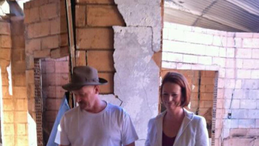 Julia Gillard is shown through the ruins of a fire devastated house in the Perth hills