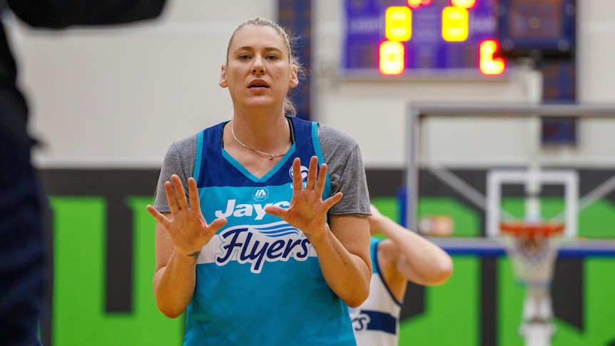 WNBL basketballer Lauren Jackson stands in a gym during training with her hands spread in front of her during a drill.