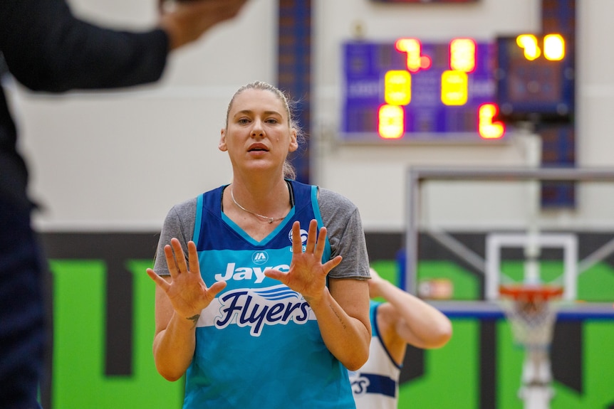 WNBL basketballer Lauren Jackson stands in a gym during training with her hands spread in front of her during a drill.