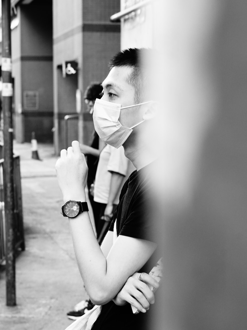 A young Chinese man was waiting for bus on Beijing street.