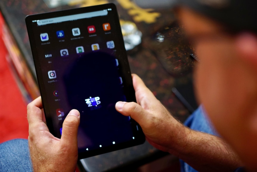 A man holding an ipad with the Zip application opening on it.