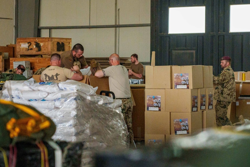 Men in combat fatigues pack cardboard boxes 