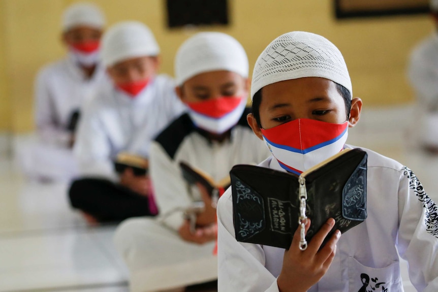 Muslim students wearing face masks practice social distancing at an Islamic boarding school.