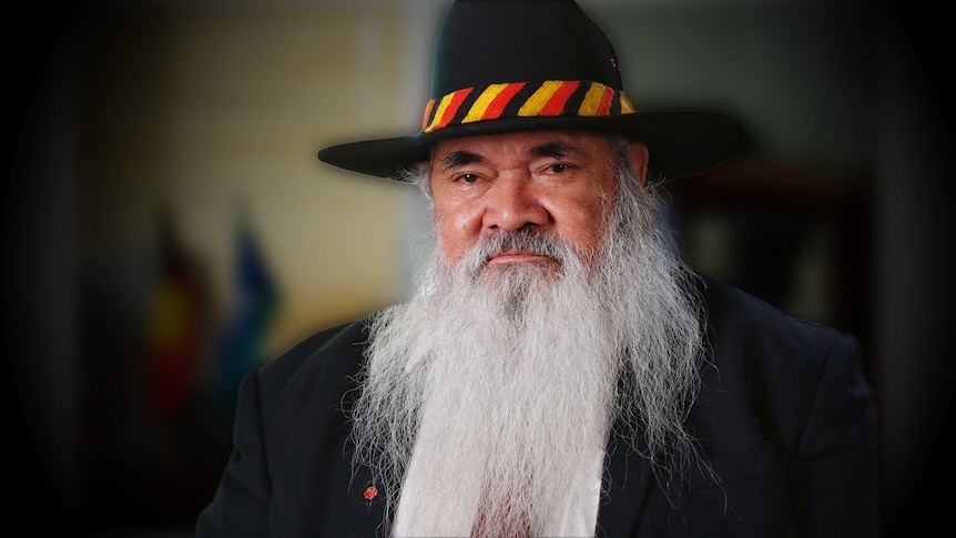 A man with a beard and a hat with the colours of the Aboriginal flag on its band.