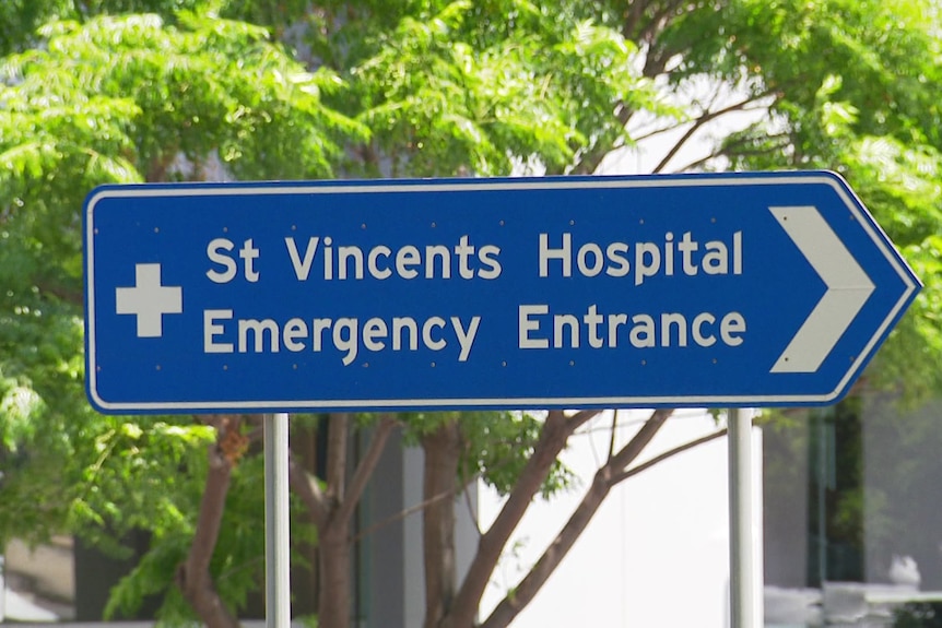 A blue pointed traffic sign indicates where to go for St Vincent's Hospital Emergency Entrance