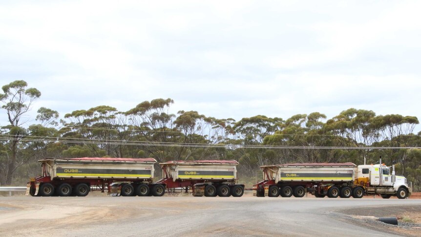 A road train with three trailers leaves a remote mine site in the outback.
