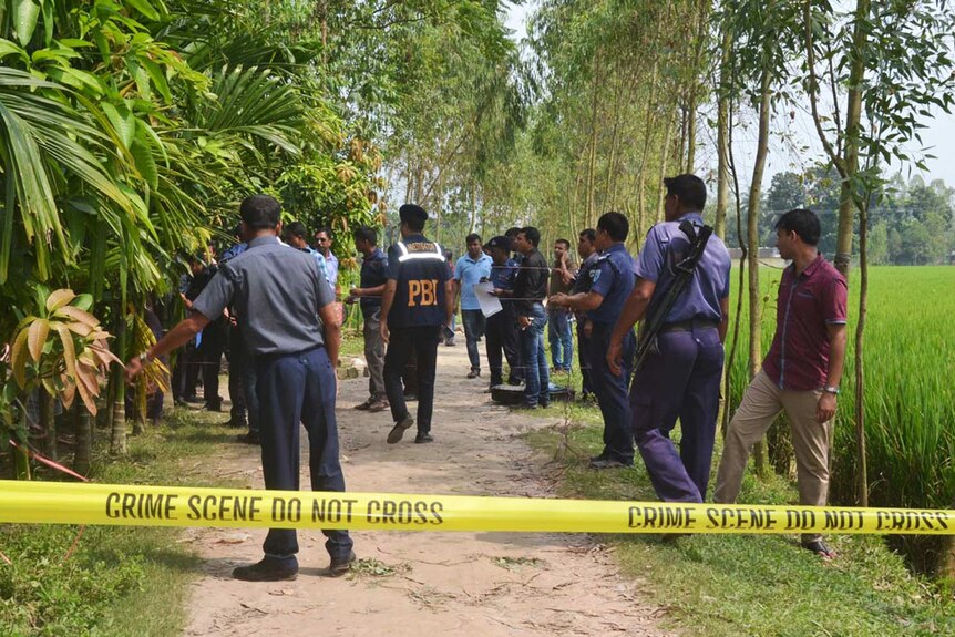 Bangladeshi police officials stand guard at crime scene