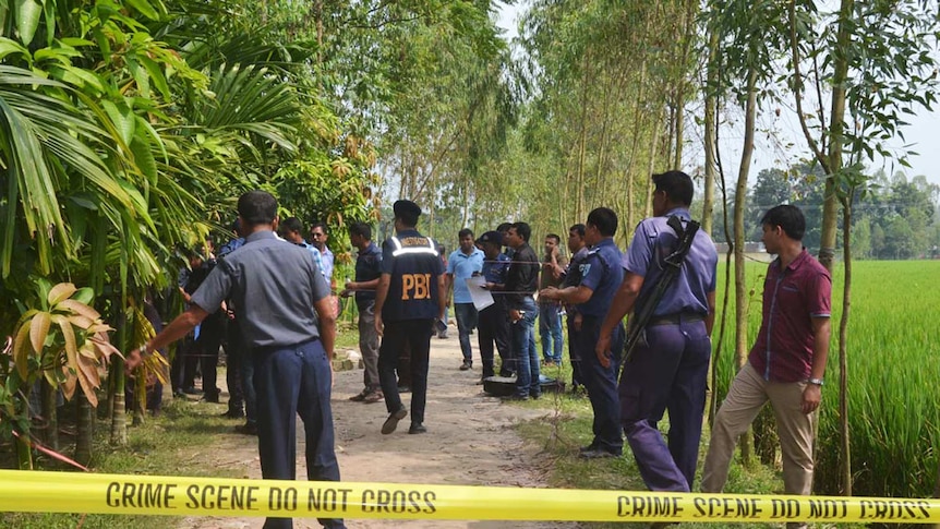 Bangladeshi police officials stand guard at crime scene