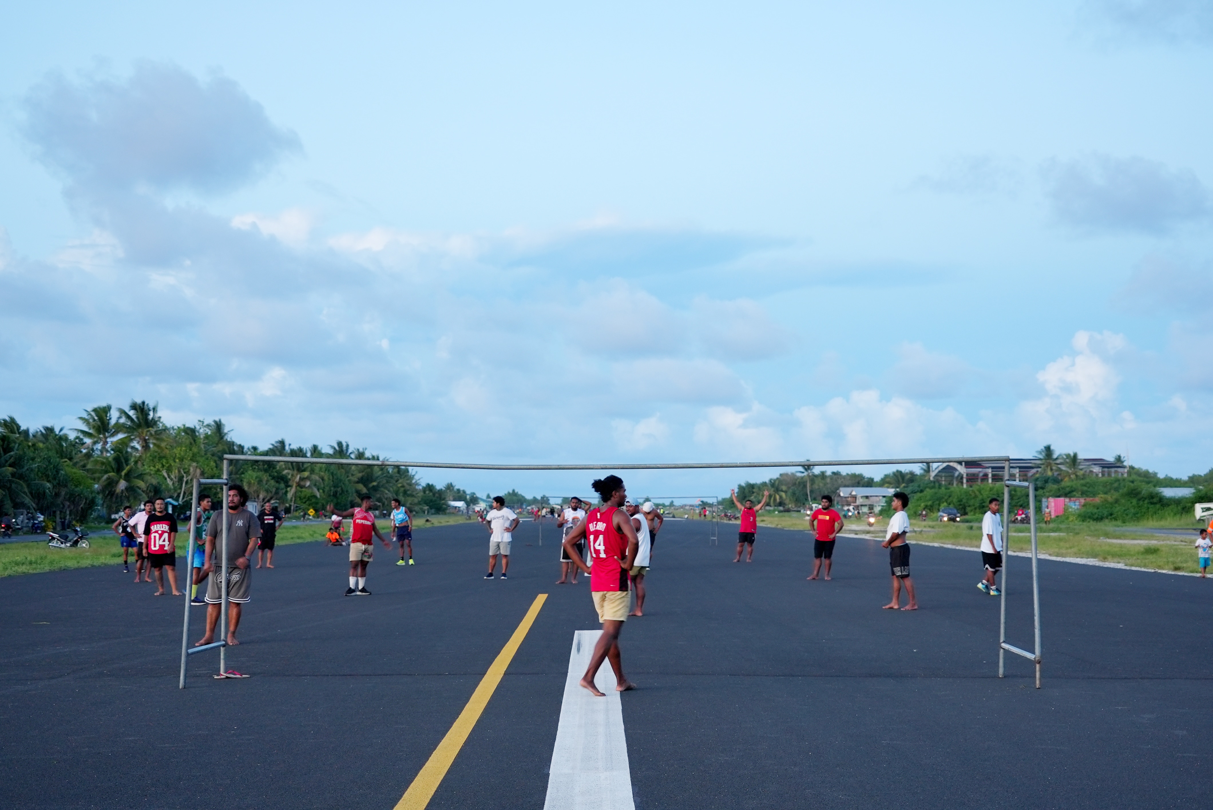Locals setup a football court on the runway tarmac at sunset.