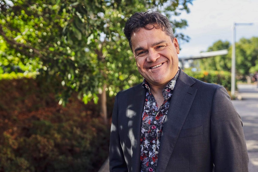 A man smiling outside a large theatre venue