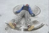 A young girl lies on her back tpo create a 'snow angel'.