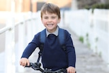 Britain's Prince Louis smiles on a red bicycle in a photo taken by his mother before his first day of school.