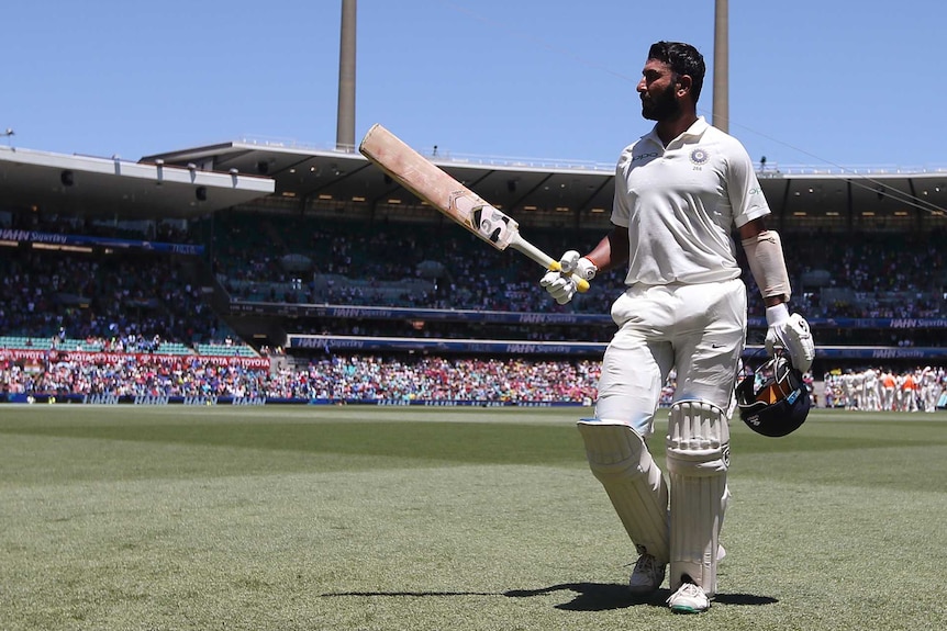 India batsman Cheteshwar Pujara walks across the SCG outfield with his bat raised after getting out in a Test against Australia.