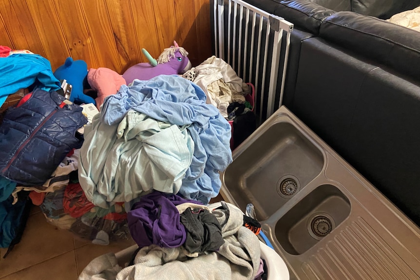 piles of clothes and washing, with a sink on the floor 