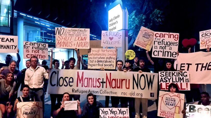 Protesters hold signs, some calling for the closure of Manus and Nauru, outside Lady Cilento Hospital.