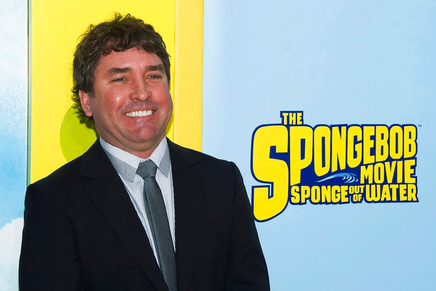 A man stands in front of a sign saying The SpongeBob Movie: Sponge Out Of Water