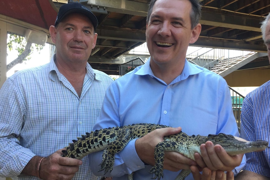 Mick Burns and Michael Gunner hold a crocodile.