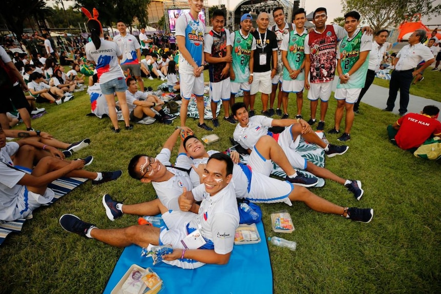 People smile while picnicking on the grass.