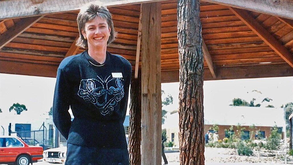 An early photo of Jane Edmanson standing under a large outdoor umbrella.