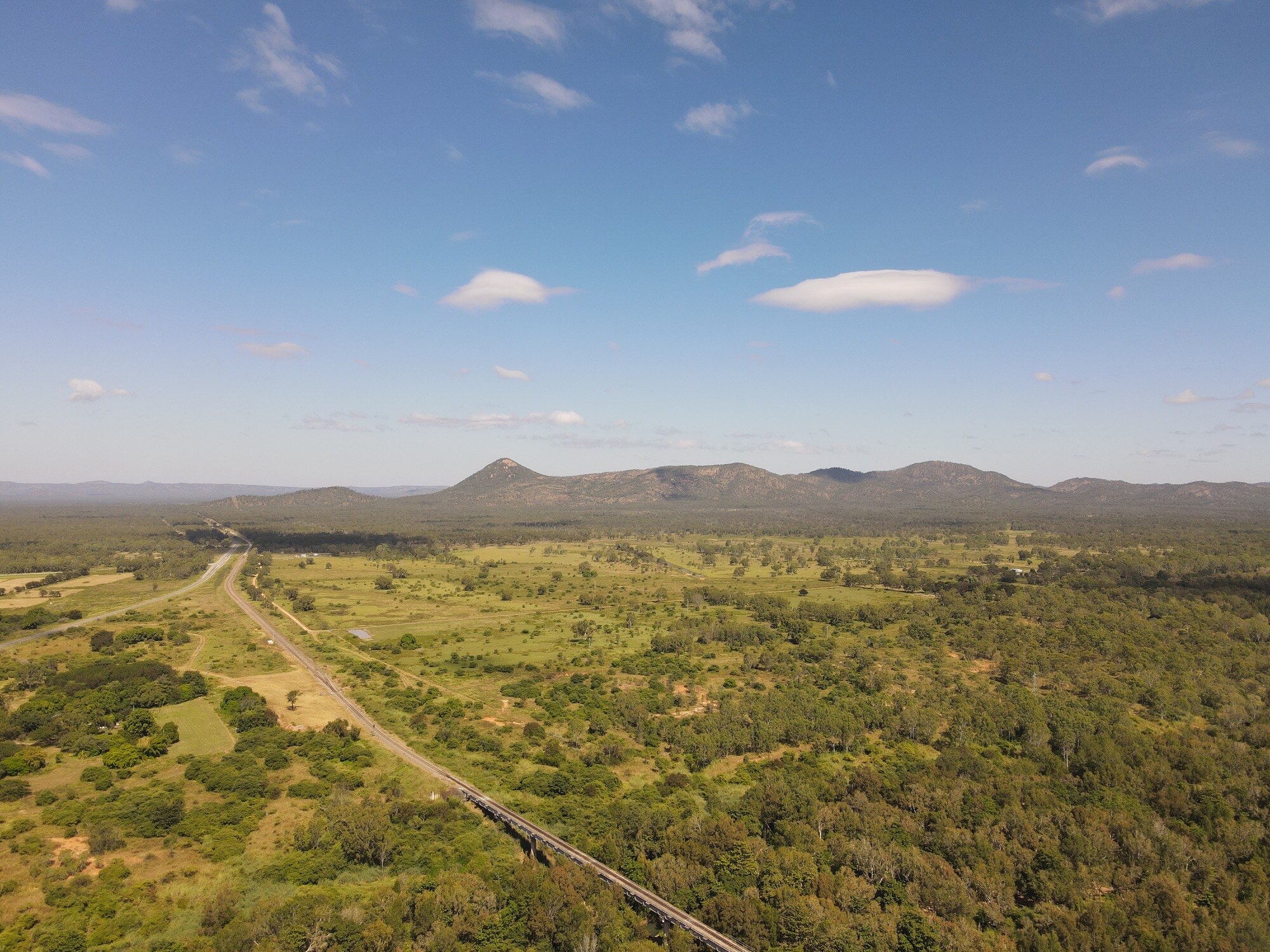 A drone shot of green bushland and mountains 