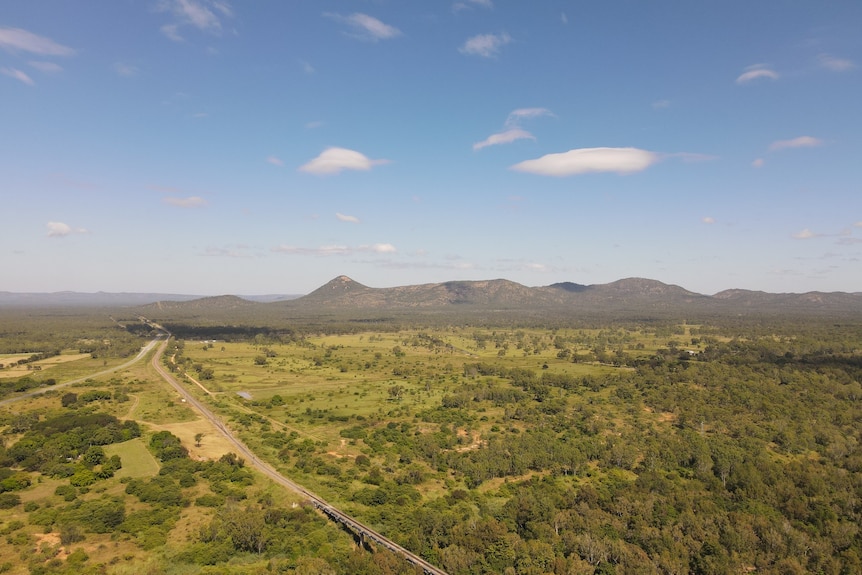 A drone shot of green bushland and mountains 