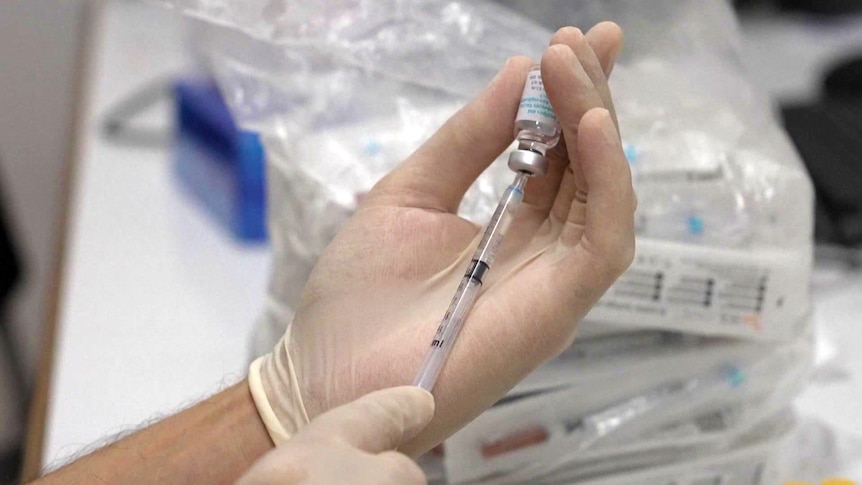 a person holding a vial of vaccine and injection