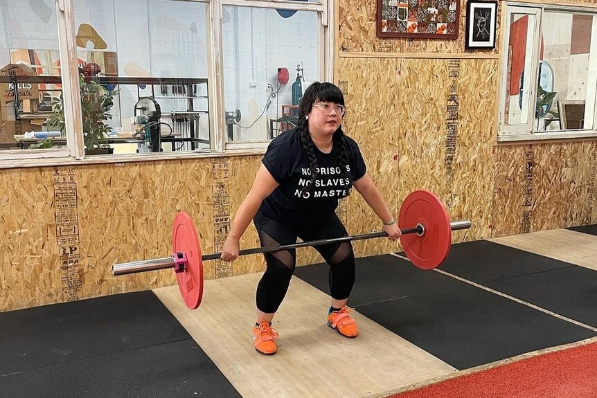 Kylie Tran lifts a barbell during Olympic Weightlifting class