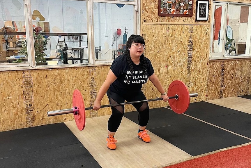 Kylie Tran lifts a barbell during Olympic Weightlifting class