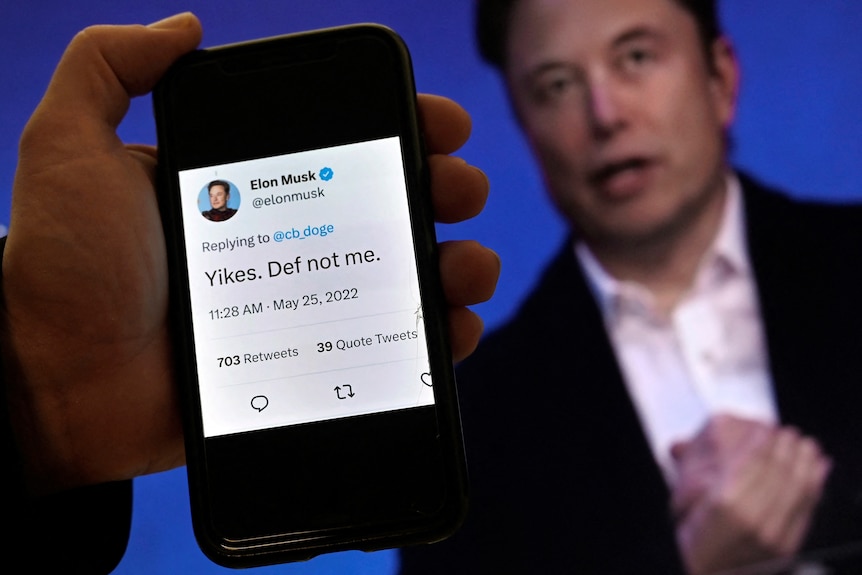 A phone displays an Elon Musk tweet saying "Yikes. Def not me" in front of an out-of-focus picture of Mr Musk.