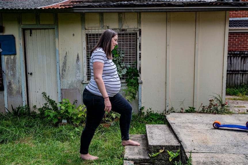 Jen Bartett, who is heavily pregnant, is pictured from the side as she steps onto a wooden platform in her garden.