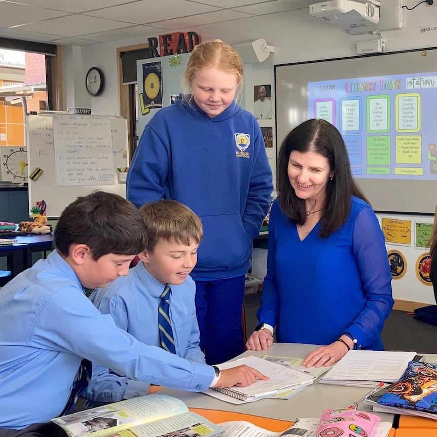 Picture of a teacher in a classroom with three students.