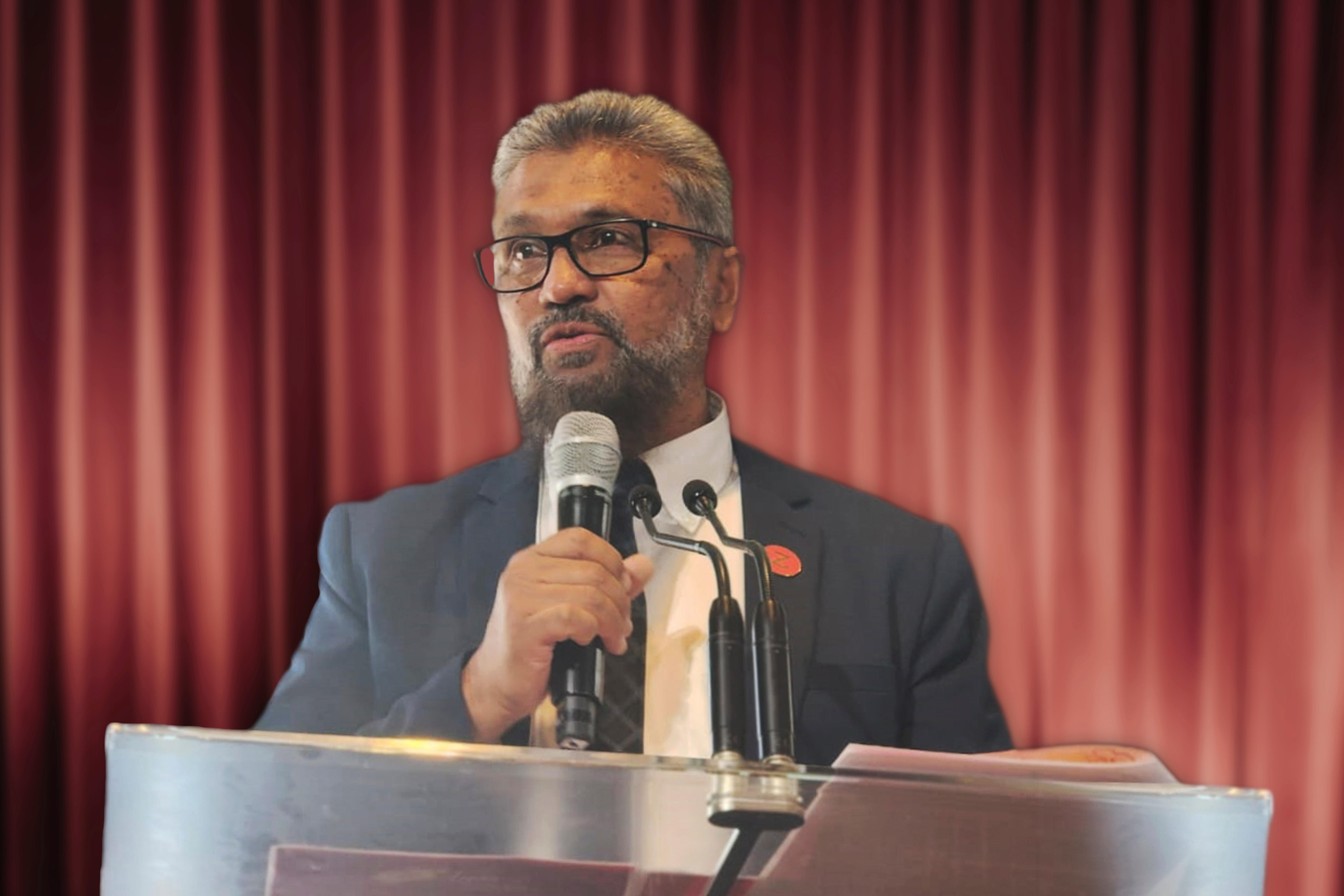 Med close up of a man wearing glasses speaking in public.