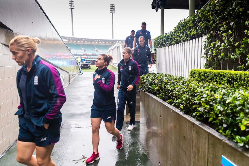 England women's players walk through the rain at the SCG after their Twenty20 World Cup semi-final was rained out.
